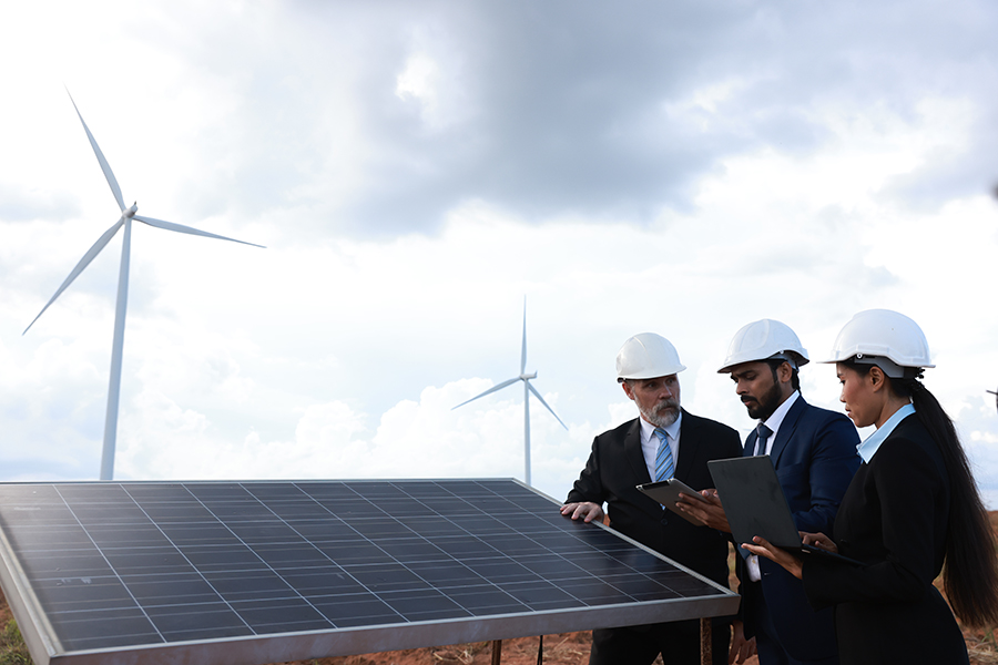 Image of business people with hardhats on site with windmills in the background