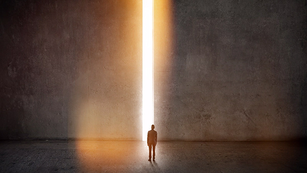 Image of a man looking out into light shining through two large walls